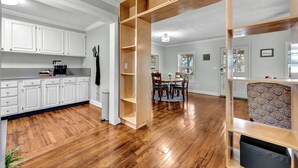 A spacious kitchen with white cabinets and a wooden dining area with a table and chairs. - University Place, family stay, practically on campus (Siloam Springs)