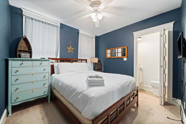 A bedroom with a bed, dresser, and a ceiling fan.