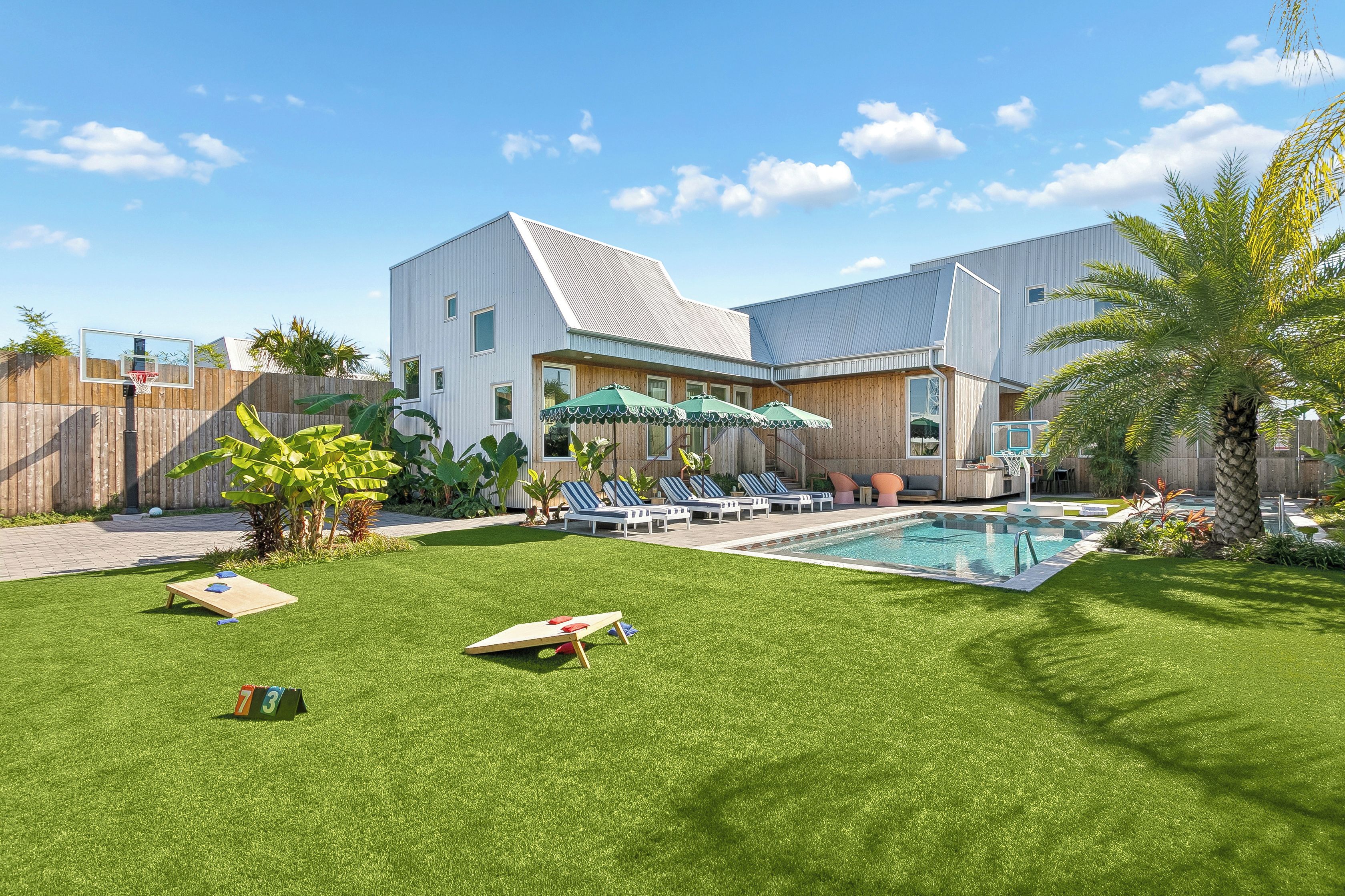 A residential property with a swimming pool, outdoor seating, and a well-maintained lawn.