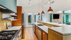 Una cocina moderna con una isla central, electrodomésticos integrados e iluminación colgante.