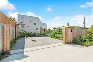 A modern residential building with a basketball hoop, a gated entrance, and a paved driveway. - The Herald at CastleDay - Private Pool, Spa (New Orleans)