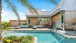 Una casa moderna con piscina, terraza de madera y zona de estar al aire libre.