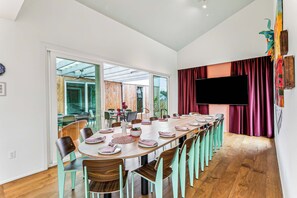 Une vaste salle à manger avec une longue table dressée pour accueillir plusieurs personnes, entourée de chaises.