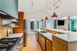 Een moderne keuken met een centraal eiland, inbouwapparatuur en hanglampen.