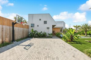 Een modern huis met een basketbalveldje, een verharde oprit en een keurig onderhouden tuin.