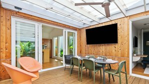 Un comedor moderno con techo de madera, un televisor de pantalla plana y una mesa preparada para cuatro comensales.
