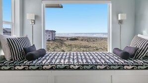 Une chambre avec une grande fenêtre donnant sur la plage et les b âtiments environnants.