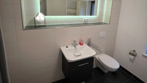 Ein modernes Badezimmer mit einem weißen Waschbecken, einem Spiegel darüber und einer Toilette.