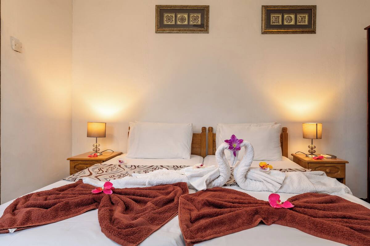 A hotel room with a bed, two nightstands, and two wall-mounted lamps.