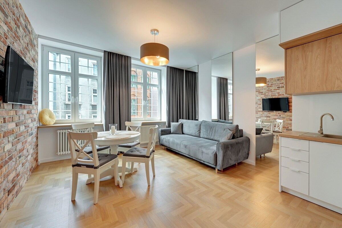 Un salon moderne avec un canapé gris, une table à manger en bois et des chaises.