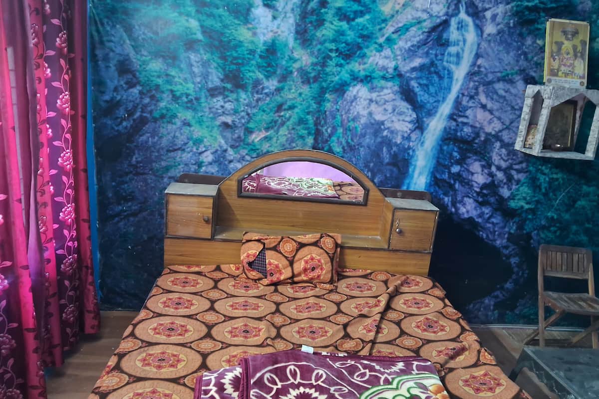 A bedroom with a bed, curtains, a wall mural, and a small wooden chair.