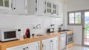 A modern kitchen with white cabinets, a microwave, a coffee maker, a stove, and a sink. - Luxury 3 bedroom apartment Agdal - 170 m2 by Masterhost (Rabat)