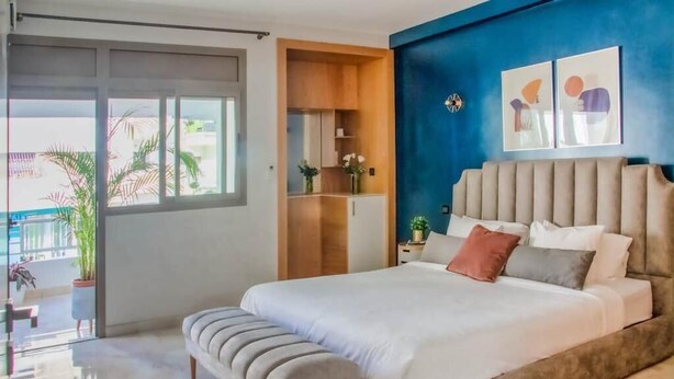 A bedroom with a large bed, a bench, a wardrobe, and a view of the outside. - Luxury 3 bedroom apartment Agdal - 170 m2 by Masterhost (Rabat)