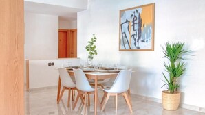 A modern dining area with a round table, white chairs, and a large painting on the wall. - Luxury 3 bedroom apartment Agdal - 170 m2 by Masterhost (Rabat)