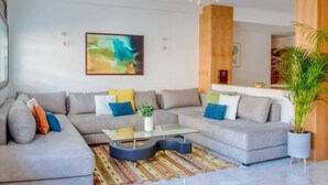A modern living room with a sectional sofa, a glass coffee table, and a large abstract painting on the wall. - Luxury 3 bedroom apartment Agdal - 170 m2 by Masterhost (Rabat)