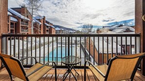 A balcony with a view of a pool and buildings. - Modern Mountain Comfort at Timber Run 304! (Steamboat Springs)