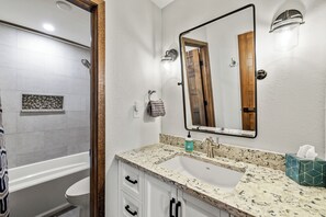 Une salle de bain avec un lavabo blanc, un miroir, un porte-serviettes et un espace douche.