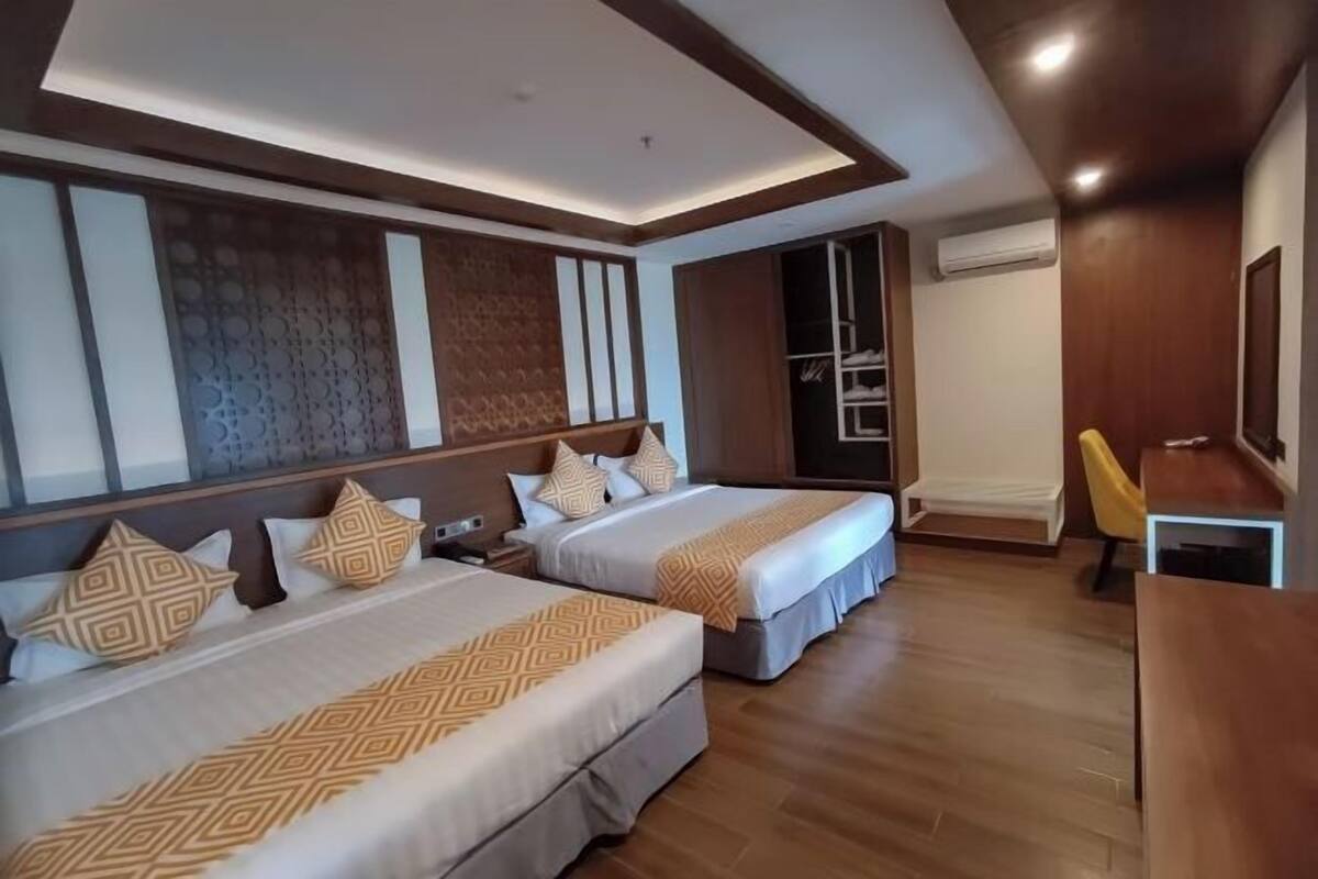 A hotel room with two beds, a desk, and a wardrobe.
