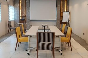 A conference room with a long table, chairs, a projector screen, and a whiteboard. - Holiday Pier Hotel (Mandalay)