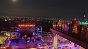 A rooftop bar with a neon sign, outdoor seating, and a view of the cityscape. - Holiday Pier Hotel (Mandalay)