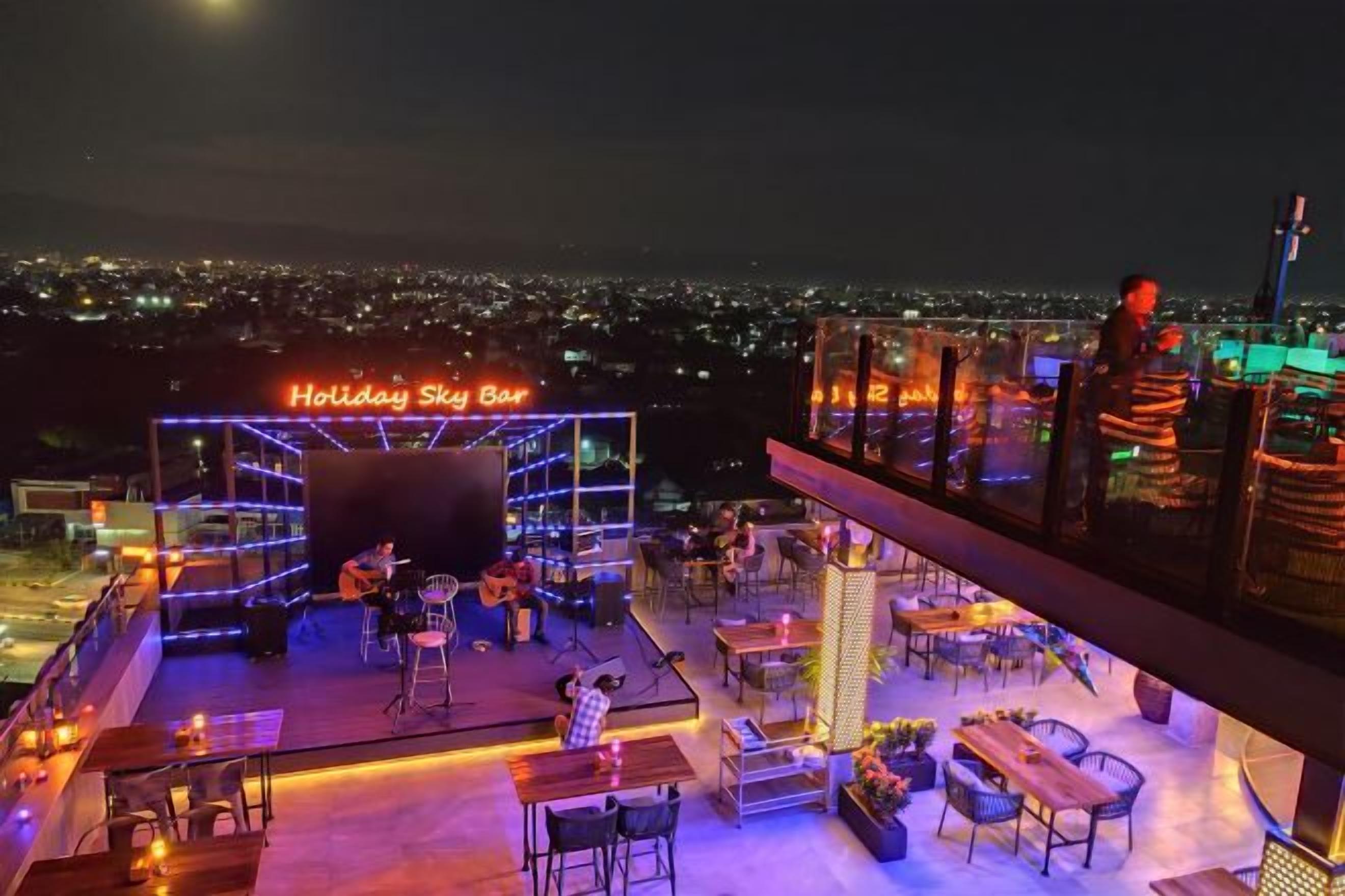 Un bar en la azotea con escenario, asientos y vistas de la ciudad.