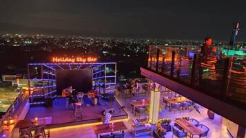 Un bar en la azotea con escenario, asientos y vistas de la ciudad.