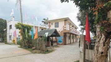 A building with a covered entrance, a flag, and a palm tree.