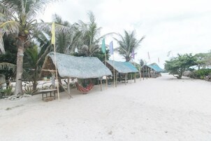 A beach with thatched-roof huts and palm trees.