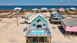 A beachfront property with multiple houses on stilts, a swimming pool, and a beach view. - New Construction! Beachfront, 3 Bedroom/3.5 Bath, Pool, Hot Tub, Pet Friendly (Dauphin Island)