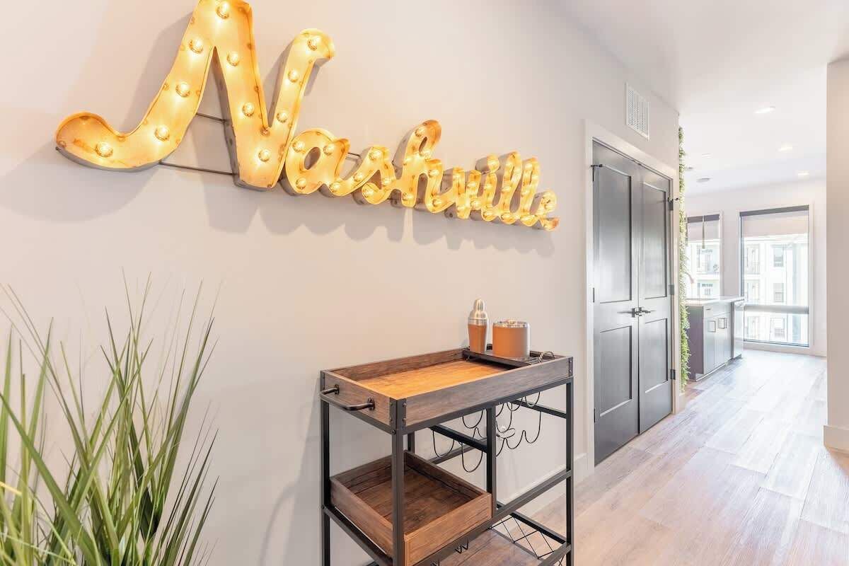 A hallway with a wall-mounted sign reading "Nashville," a wooden console table with a tray, and a potted plant.