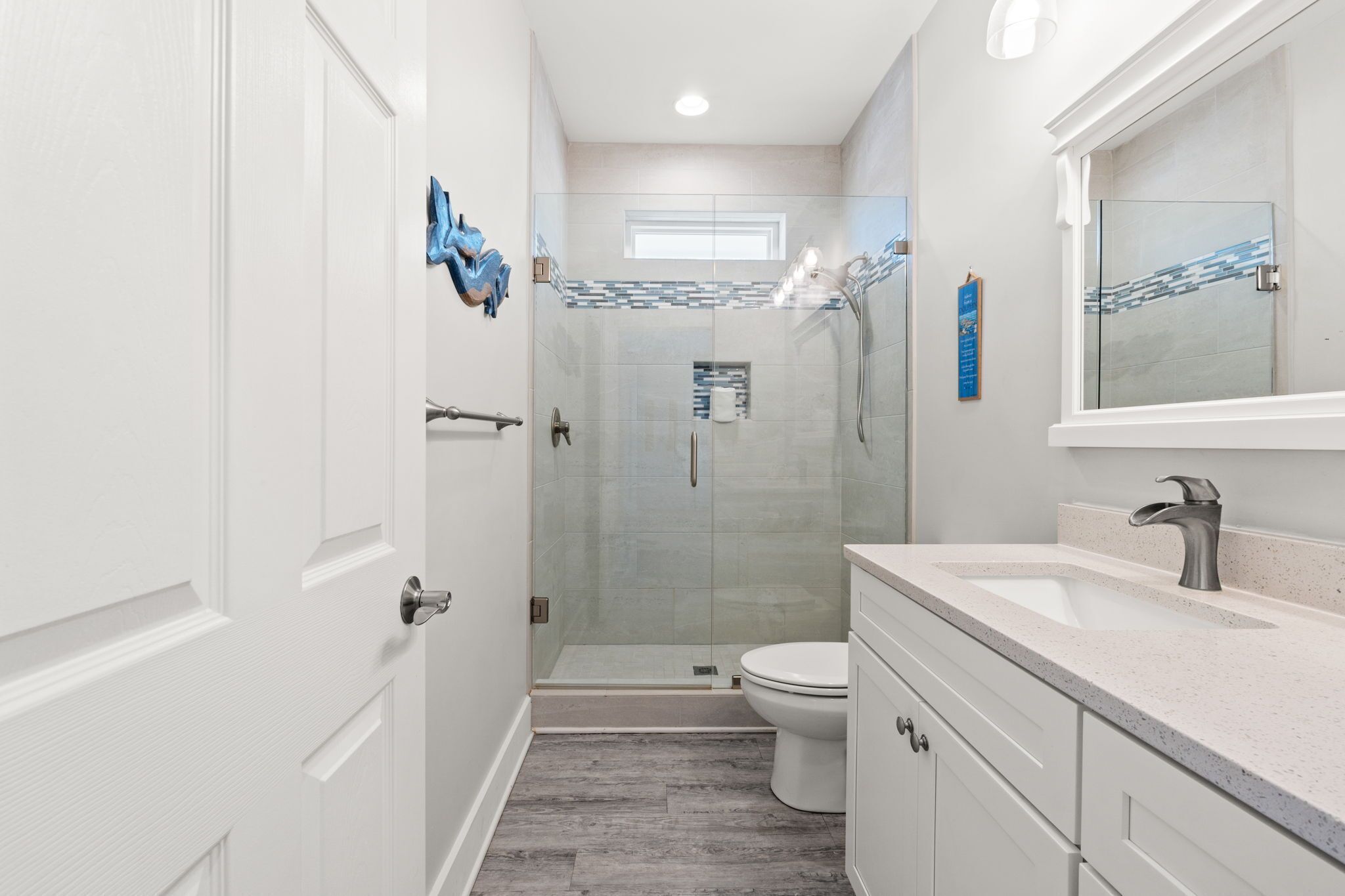 A modern bathroom with a glass shower enclosure, a white toilet, and a vanity with a sink.