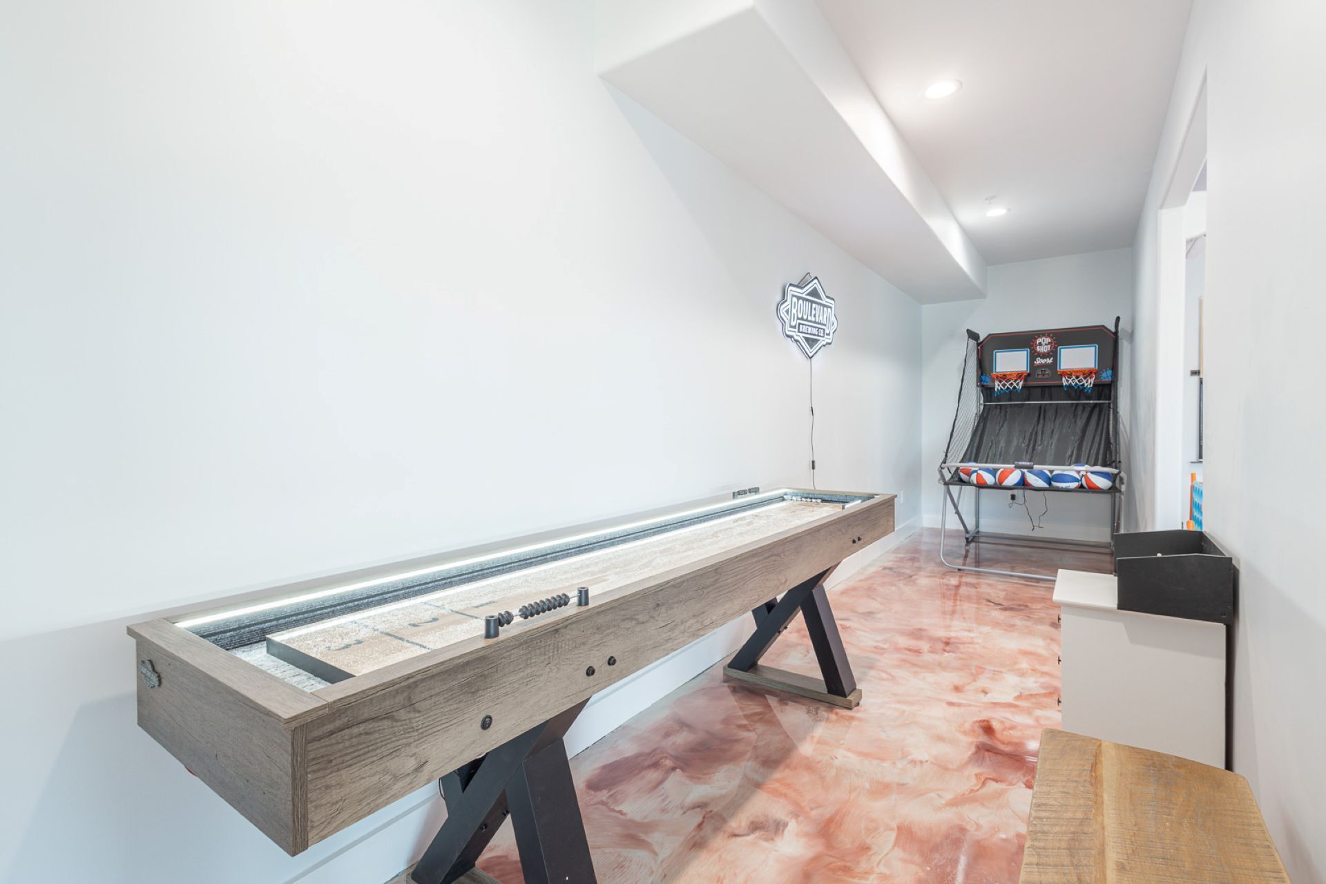 A room with a foosball table, a bowling alley, and a wall-mounted sign.