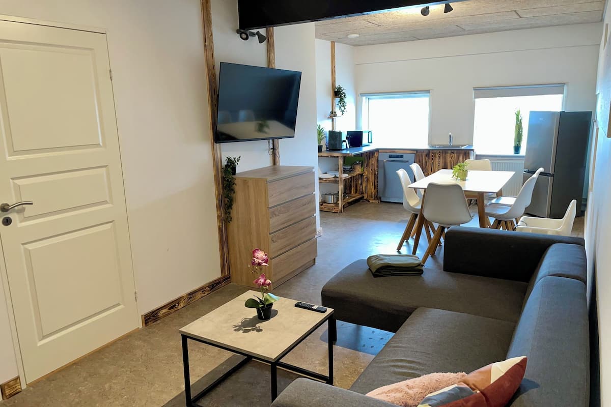 A modern living room with a sofa, a coffee table, and a TV mounted on the wall.