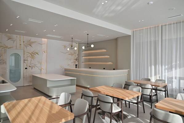 L’intérieur d’un restaurant moderne, avec un comptoir d’accueil, des tables et des chaises.