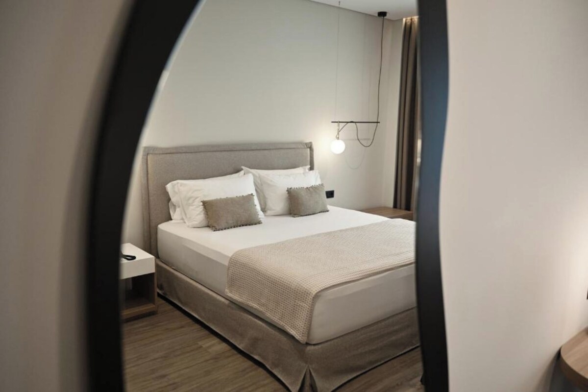 Ein ordentlich eingerichtetes Schlafzimmer mit Bett, Nachttisch und Wandleuchte.