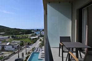 Uma varanda com vista para uma piscina e uma estrada com edifícios ao fundo.