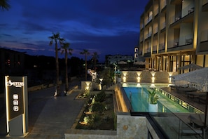 Hotel com piscina, área de estar externa e entrada bem iluminada.