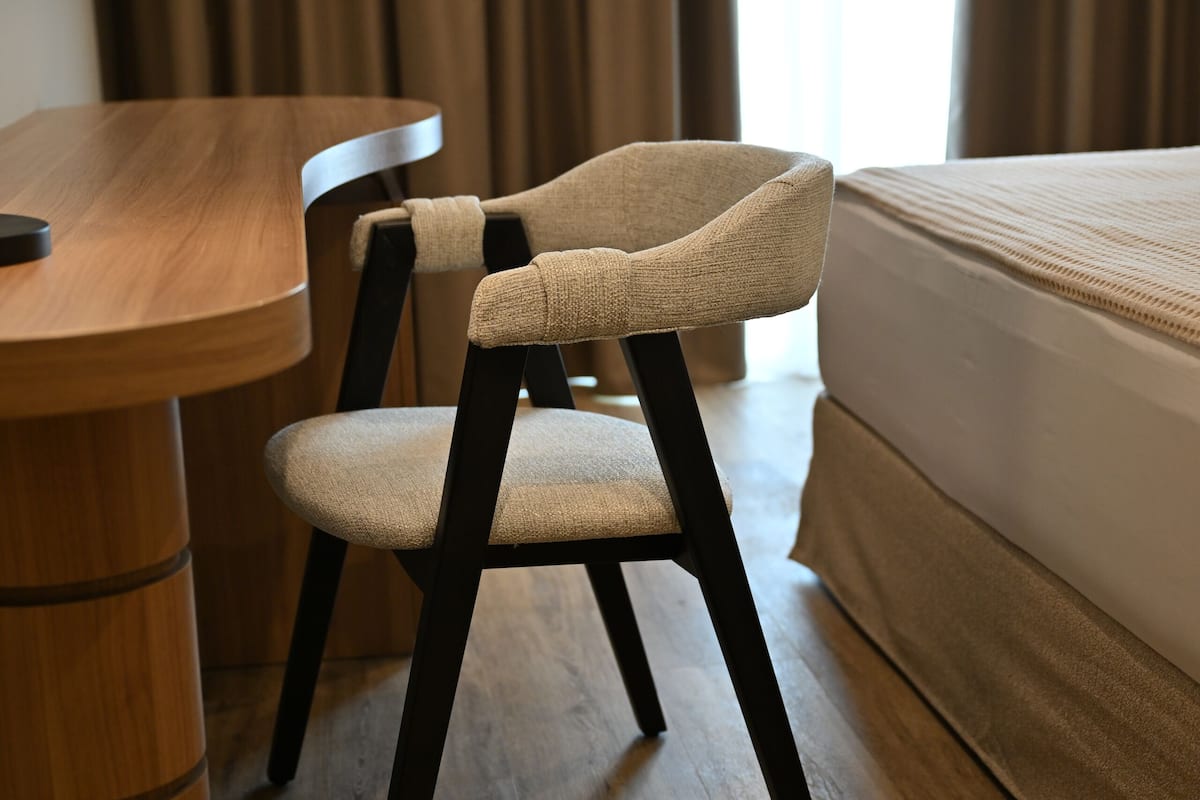 A wooden desk with a lamp, a chair, and a bed in a hotel room.