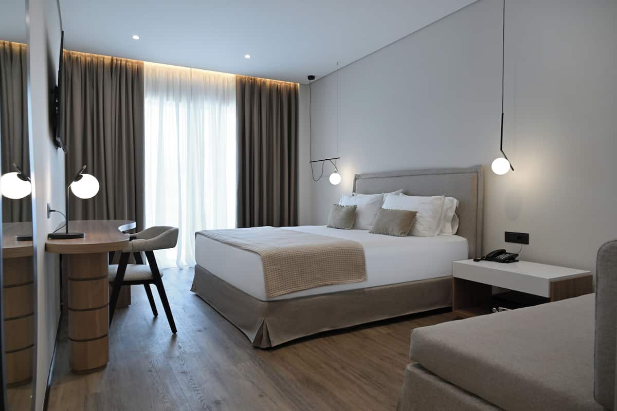 A modern hotel room with a large bed, bedside tables, a desk, and a chair.
