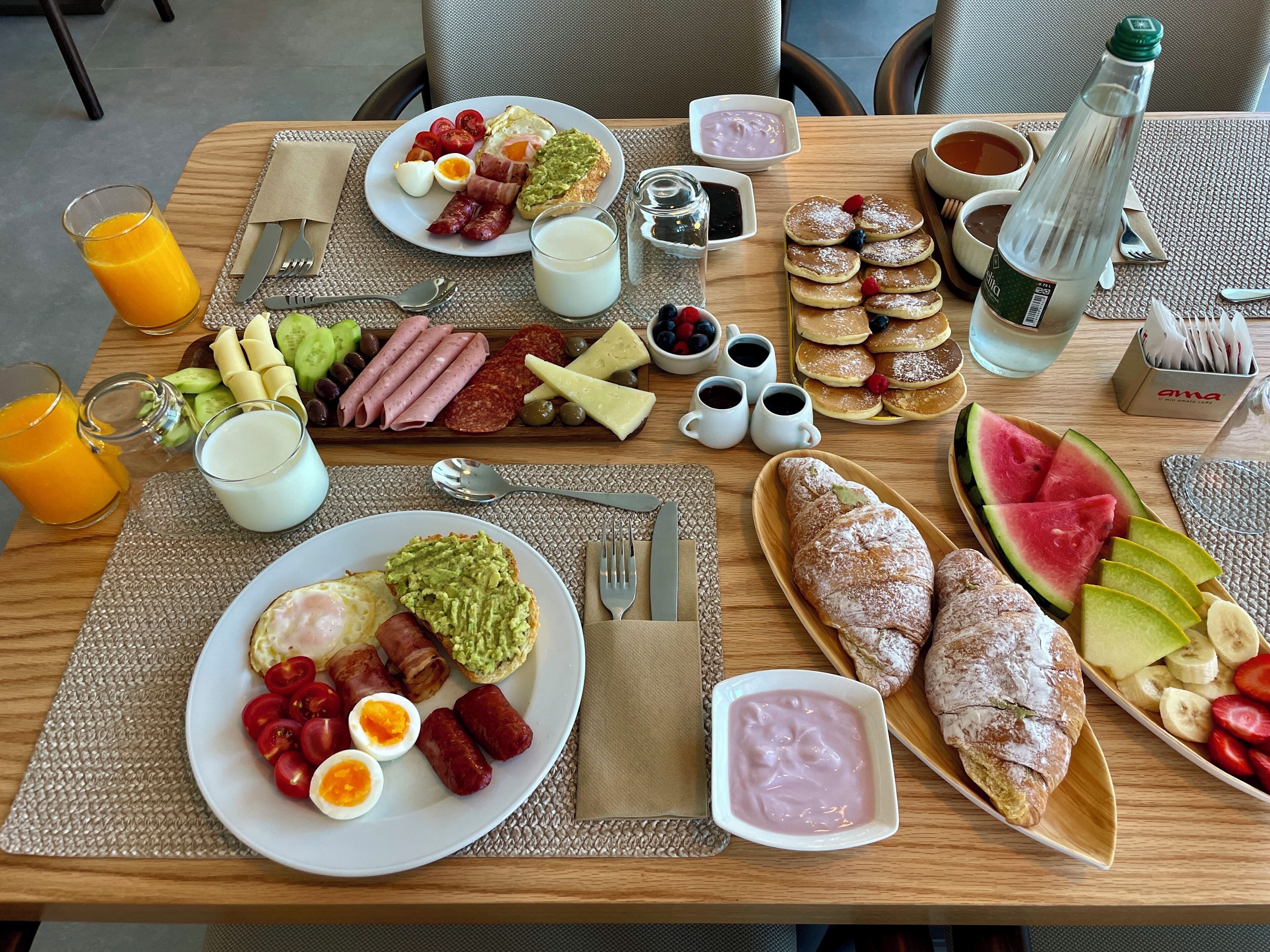 En morgenmadsbuffet med et udvalg af mad, drikkevarer og tilbehør.