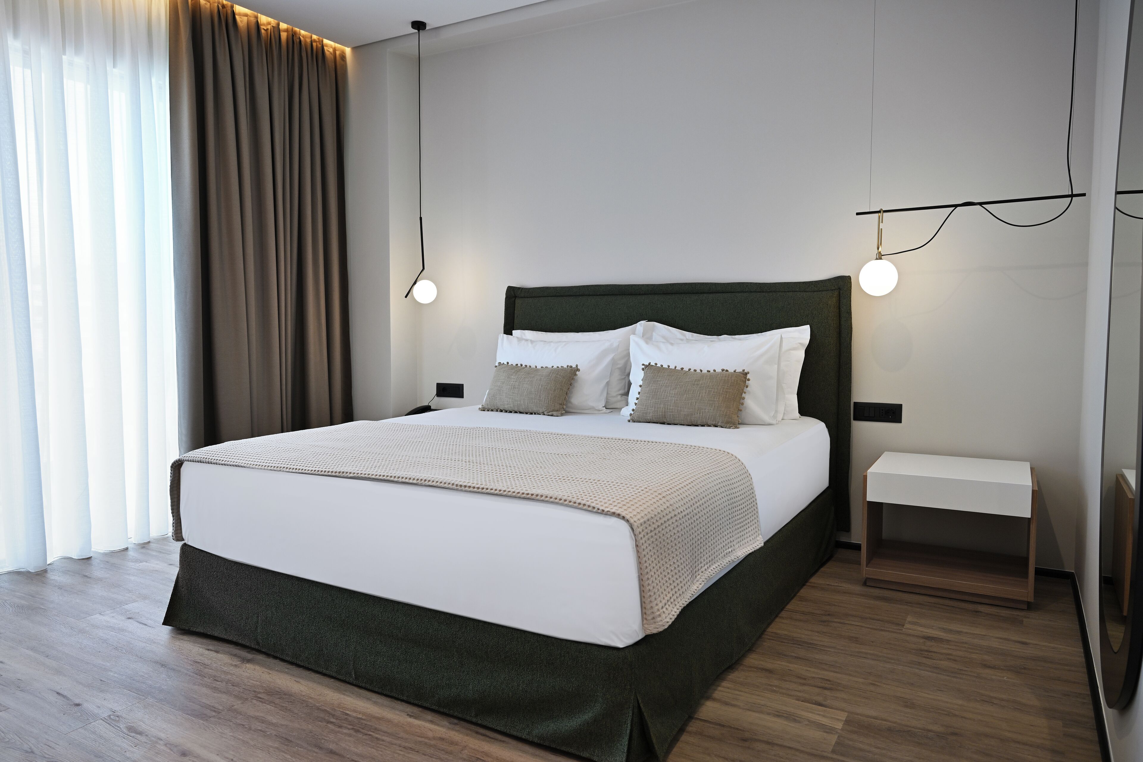 Een moderne slaapkamer met een groot bed, nachtkastjes en een bijzettafel.