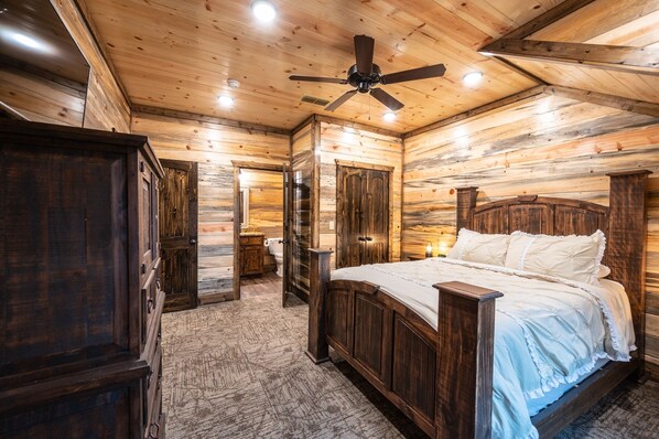 A wooden cabin bedroom with a bed, a ceiling fan, and a large wardrobe. - The Rusty Windmill In Broken Bow/ Hochatown (Broken Bow)
