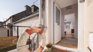Een balkon met een reddingsboei, een bloempot en uitzicht op een gebouw met een deur naar een kamer.