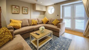 A living room with a beige sectional sofa, a wooden coffee table, and a blue patterned rug. - Bay Tree Cottage Rhondda Valley by STAE-Homes (Rhondda Cynon Taff)