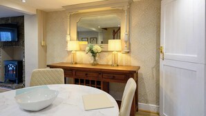 A dining area with a marble table, a wooden console table with lamps, and a large mirror above. - Bay Tree Cottage Rhondda Valley by STAE-Homes (Rhondda Cynon Taff)