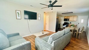 Una sala de estar moderna con un sofá gris, una mesa de centro y un televisor de pantalla plana montado en la pared.