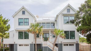 Ein modernes, zweistöckiges Haus mit einer zentralen Treppe, großen Fenstern und einem gepflasterten Auffahrt.