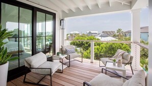 Ein Balkon mit Holzboden, weißen Möbeln und Blick auf Nachbarhäuser.