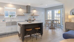 A modern kitchen with a central island, bar stools, and a dining area with a round table and chairs.