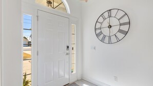 A white door with a small window, a wall-mounted clock, and a ceiling light fixture.